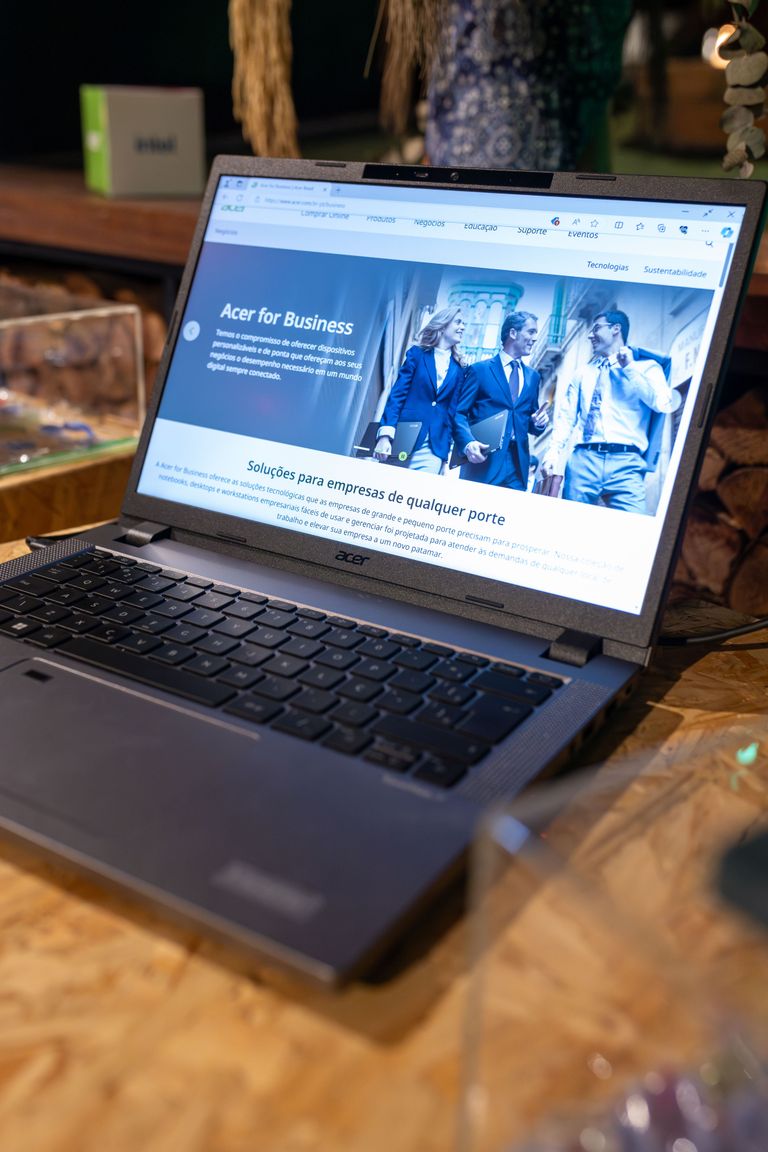 An open Acer laptop displaying a business webpage, set on a wooden desk indoors.