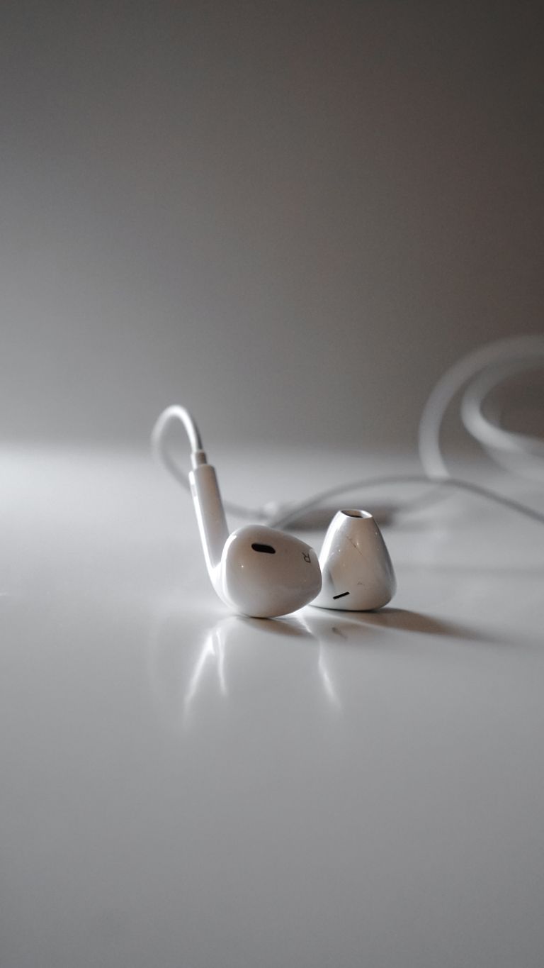 Detailed close-up of white earphones on a white surface, highlighting modern audio technology.