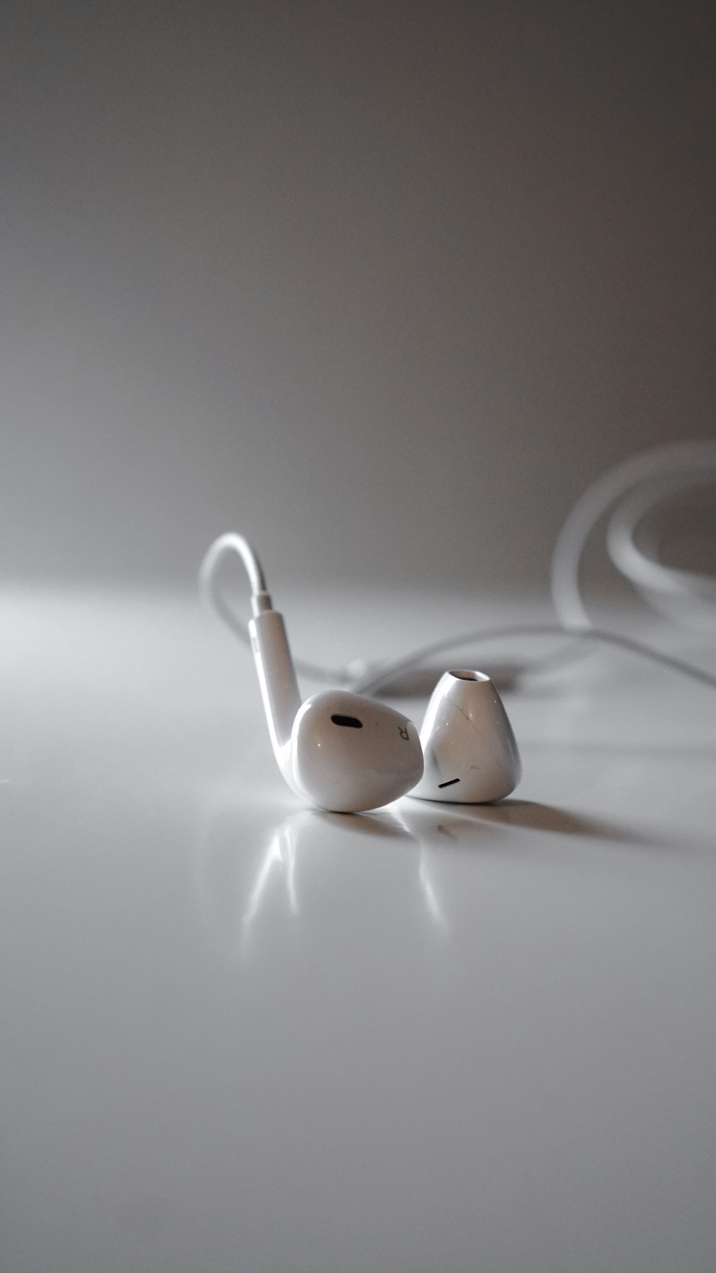 Detailed close-up of white earphones on a white surface, highlighting modern audio technology.