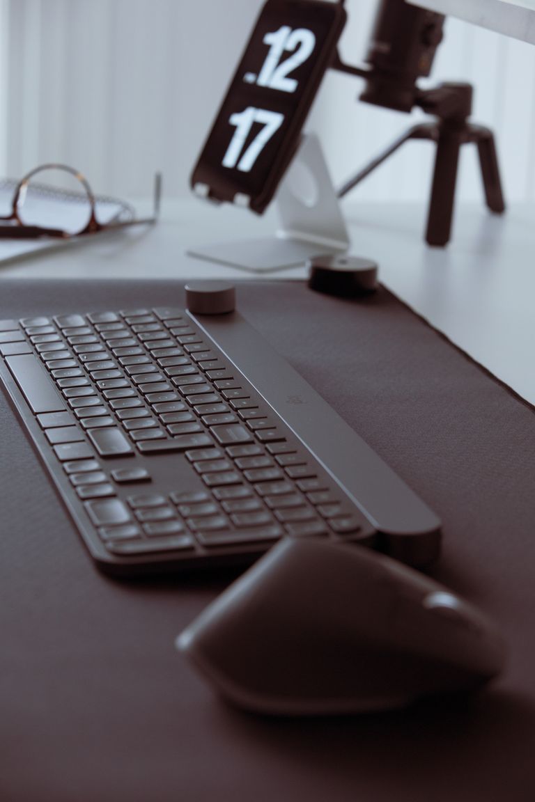 Stylish office setup featuring a sleek keyboard and mouse with a smartphone on a stand in the background.