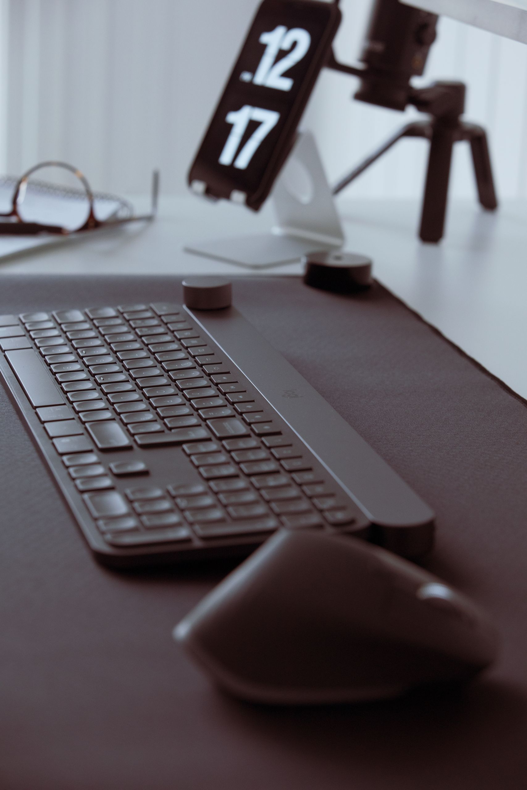 Stylish office setup featuring a sleek keyboard and mouse with a smartphone on a stand in the background.